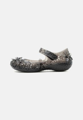 Black translucent jelly flat with a floral cutout pattern and a strap across the top, decorative flower accents on the sides for a girl&rsquo;s shoe